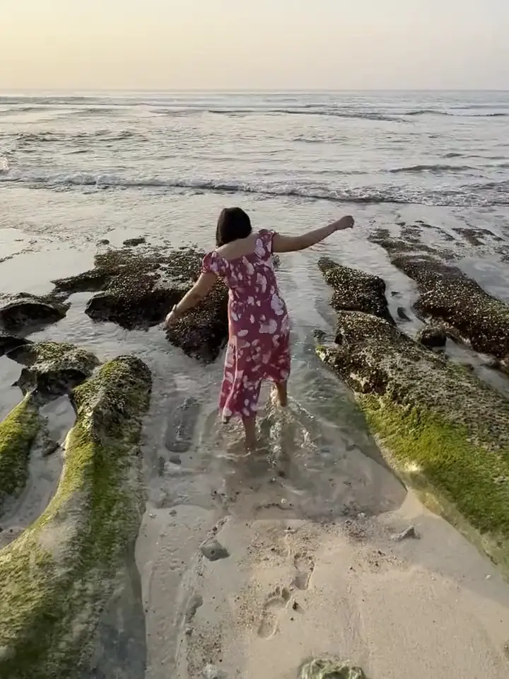 Berjalan di pantai di antara bebatuan.