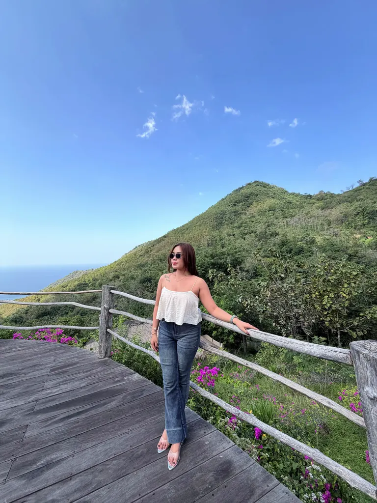 Potret di dek dengan bukit hijau dan laut.